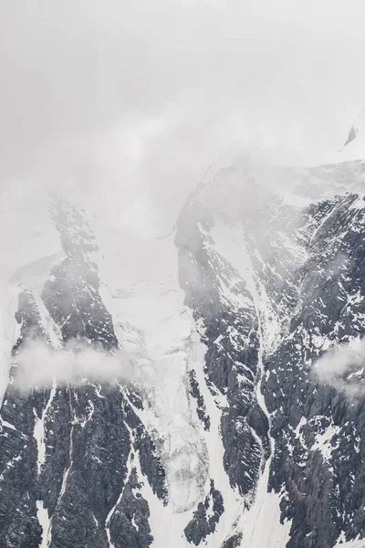 低雲の中に大きな山の上に大規模な氷河と大気のミニマルなテクスチャ高山風景 雪に覆われた山の背景 氷の上の亀裂 標高の高い霧深い景色 — ストック写真