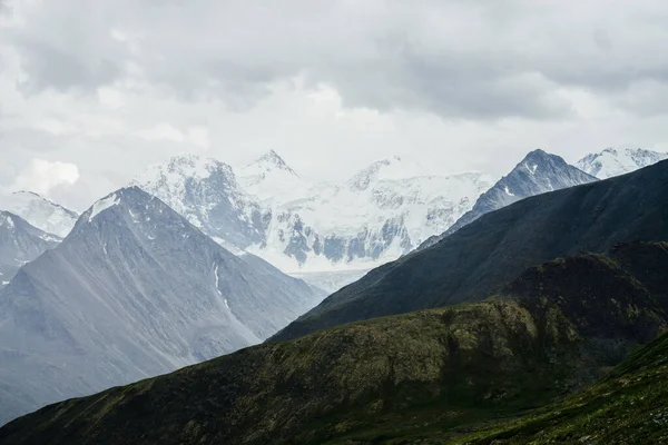 在阴云密布的大岩石后面的大雪山山脉上 美丽的景色可以看到巨大的冰川 巨大的岩石山的尖尖顶部 迷人的高地之美 大气高山景观 — 图库照片