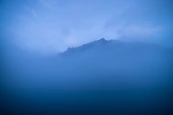 Gran Montaña Rocosa Medio Del Agua Entre Nubes Bajas Atardecer — Foto de Stock