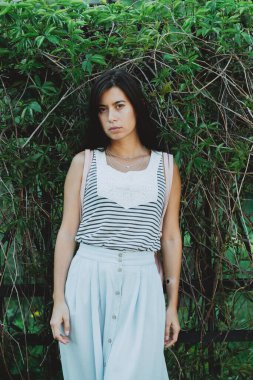 Yazın yeşillikler arasında bahçede tek başına gezen ilham verici kız. İlkbaharda yeşil çitin yanında siyah uzun saçlı çekici bir köylü kızı. Kız üzümlerinin arka planında güzel bir kadın portresi