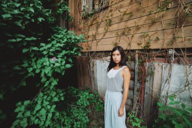 İlkbaharda terk edilmiş evin yakınında, kız gibi üzümlü ve leylak çalılı genç bir kız. Ahşap duvarın arka planında kırık camları olan güzel bir köylü kızı. Yeşilliklerin arasında eski bir ev.