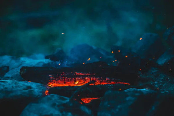 火の近くで焼かれた鮮やかな色付きの薪 キャンプファイアと青煙のオレンジの炎と大気暖かい背景 たき火の想像を絶するフルフレームイメージ 美しい火災でログを燃焼 — ストック写真