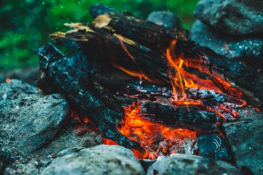 Yanan odun odunları yakın plan ateşte yanmış. Atmosferik arka plan ve turuncu kamp ateşi. Bokeh 'te kıvılcımlar saçan şenlik ateşinin tam kare görüntüsü. Parlayan közlerin sıcak girdabı ve havadaki küller