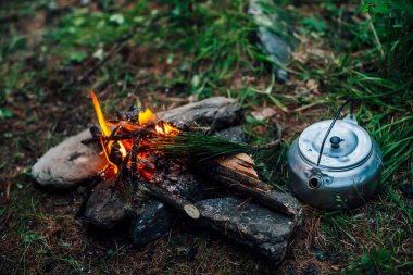 Kamp ısıtıcısı kamp ateşinin yanında. Vahşi doğada rahat bir kamp yeri. Kamp ateşinin harika akşam atmosferik arka planı. Küçük sihirli şenlik ateşinin güzel alevi. Ateşli romantik sıcak bir yer.