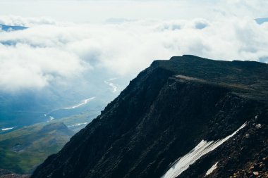 Alçak bulutların arasında yüksek siyah kayalıkları olan muhteşem bir manzara. Engebeli siyah taşlardan oluşan karanlık bir dağ ve vadide nehirli bulutlardan oluşan bir deniz. Derin uçurum ve bulutlu okyanus. Karanlık atmosferik dağ manzarası