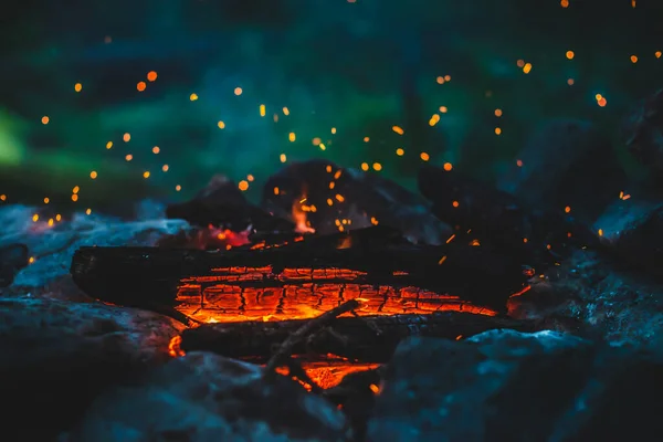火の密室で焼かれた鮮やかな色付きの薪 キャンプファイアのオレンジ色の炎で大気中の背景 空中で輝くメンバーとたき火の素晴らしいフルフレームイメージ 暖かい丸太 明るい火花Bokeh — ストック写真