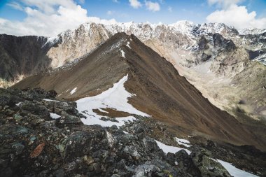 Atmosferik minimalist dağ manzarası ve muazzam karlı dağ sıraları. Combe Rocky Hill 'de kar ya da ateş. Mavi gökyüzü karlı tepenin üzerinde. Kaya akıntısı. Yüksek irtifada görkemli manzara.