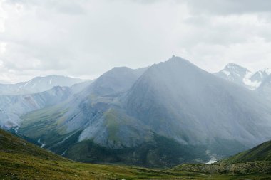 Geçitten büyük dağa atmosferik alp manzarası kasvetli bulutlu gökyüzünün altında keskin bir tepe noktası var. Harika dev sivri kayalık tepeler ve dağ geçidinin arkasındaki karlı dağlar. Dağların muhteşem güzelliği.