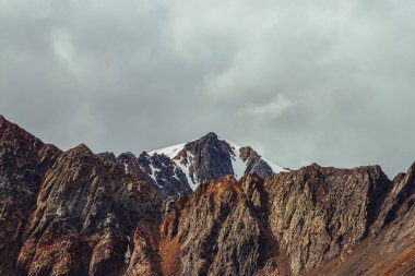 Devasa buzula muhteşem bir manzara. Sivri uçlu kayaların ardında güzel bir dağ duvarı ve üstünde keskin taşlar var. Atmosferik dağ manzarası. Bulutlu gökyüzünün altında canlı, kayalık dağlar..