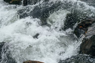 Dağ nehrinin su tabancasının tam çerçeveli arka planı. Akıntılı dağ deresinin güçlü su akıntısı. Dağ deresinin doğal desenli akışı. Hızlı desen yakın plan.