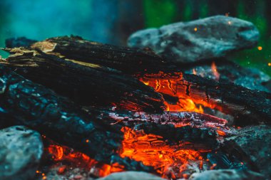 Yanan odun odunları yakın plan ateşte yanmış. Atmosferik sıcak arka plan, turuncu kamp ateşi ve mavi duman. Şenlik ateşinin mükemmel tam kare görüntüsü. Güzel ateşte yanan odunlar.