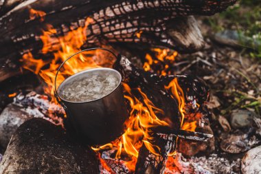 Çaydanlık yanıyor. Vahşi doğada yemek pişirmek. Şenlik ateşinde büyük, güzel bir kütük yanığı. Vahşi doğada hayatta kalmak. Caldron 'lu harika bir alev. Esrar yanıyor. Kamp ateşi arka planı.