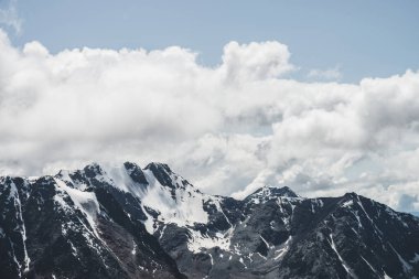 Atmosferik minimalist alp manzarası karlı dağ zirvesinde asılı devasa bir buzulla. Buzul sınırında büyük bir balkon. Karlı dağların üzerindeki bulutlu gökyüzü. Yüksek irtifada görkemli manzara.