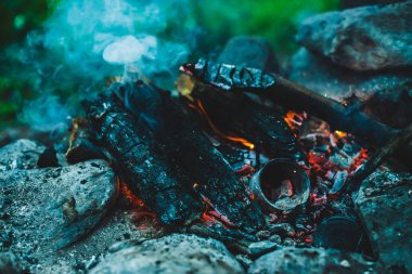 Yanan odun odunları yakın plan ateşte yanmış. Atmosferik sıcak arka plan, turuncu kamp ateşi ve mavi duman. Şenlik ateşinin mükemmel tam kare görüntüsü. Güzel ateşte yanan odunlar.