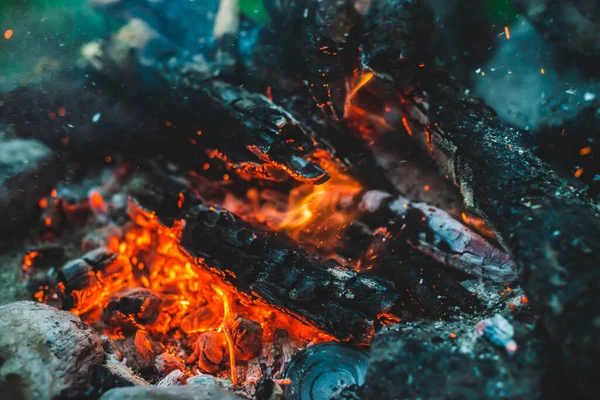 火の密室で焼かれた鮮やかな色付きの薪 キャンプファイアのオレンジ色の炎で大気中の背景 ボケで火花とたき火のフルフレームイメージ 輝くメンバーと空気中の灰の暖かい渦 — ストック写真