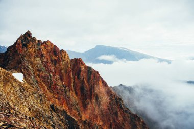 Bulutlu gökyüzünde güzel, sivri, kayalık bir zirve. Canlı, sivri, kayalık bir tepe. Dev bir taş parçası. Atmosferik minimalist alp manzarası. Gökyüzünde keskin kayalık bir dağ tepesi. Muhteşem dağlık manzara.