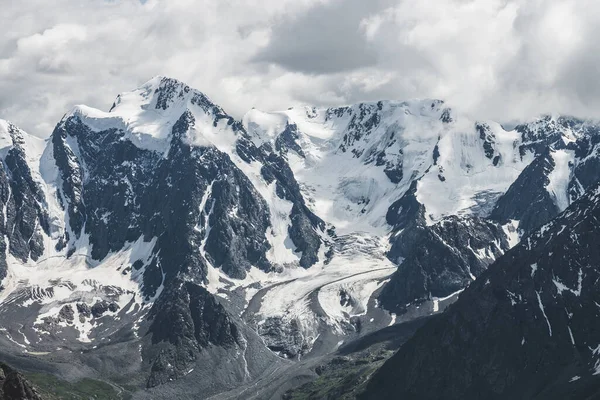 大气高山景观 巨大的冰川悬挂在巨大的山上 山坡上的大冰川舌 雪山间的低云 冰上的裂缝高空壮丽的风景 — 图库照片
