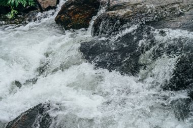 Dağ nehrinin su tabancasının tam çerçeveli arka planı. Akıntılı dağ deresinin güçlü su akıntısı. Dağ deresinin doğal desenli akışı. Hızlı desen yakın plan.
