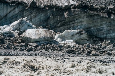 Büyük buzul duvarının doğal dokusu ve yarıklar yakın planda. Atmosferik arka planda, buzdan kayaların yanında çatlaklar olan buz kırıkları var. Buzul yüzeyine yakın buz ve taşlardan oluşan büyük bir barış..