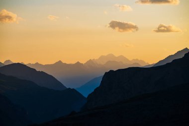 Renkli şafak manzarası güzel mavi dağ siluetleri ve bulutlu altın eğimli gökyüzü. Çok renkli gün batımlı canlı bir dağ manzarası. Manzaralı gün doğumu görünümü dağ sırasına.