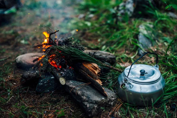 Camping kettle near small camp fire close-up. Cozy camping place in wild. Wonderful evening atmospheric background of campfire. Beautiful flame of small magic bonfire. Romantic warm place with fire.