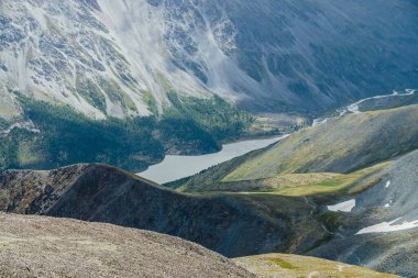 Dağlar, göl ve ormanla kaplı dev yamaçlarla muhteşem bir hava manzarası. Atmosferik dağlık arazi, büyük kayalık tepeler ve büyük dağlar. Dağ yamacında doğa desenleri