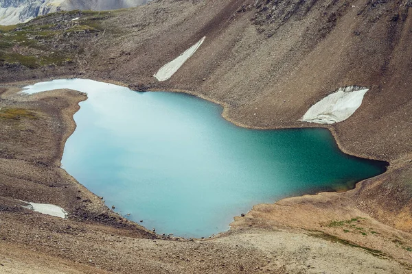 在高山中的高山山谷中 大气简约的高山景观和美丽的冰川湖 在冰川石质岩石坡之间的山湖周围 积雪片片 美丽的风景 — 图库照片
