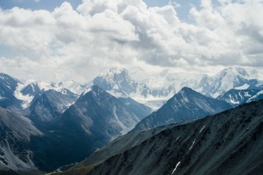 Gri bulutlu gökyüzünün altında kocaman buzul dağları olan muhteşem dramatik alp manzarası. Karlı dağlara ve buzullara harika bir dağ manzarası. Büyük kayalar ve buzullarla atmosfer manzarası.