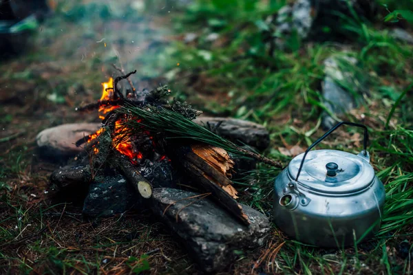 Camping kettle near small camp fire close-up. Cozy camping place in wild. Wonderful evening atmospheric background of campfire. Beautiful flame of small magic bonfire. Romantic warm place with fire.