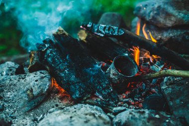 Yanan odun odunları yakın plan ateşte yanmış. Atmosferik sıcak arka plan, turuncu kamp ateşi ve mavi duman. Şenlik ateşinin hayal edilemez tam kare görüntüsü. Güzel ateşte yanan odunlar.