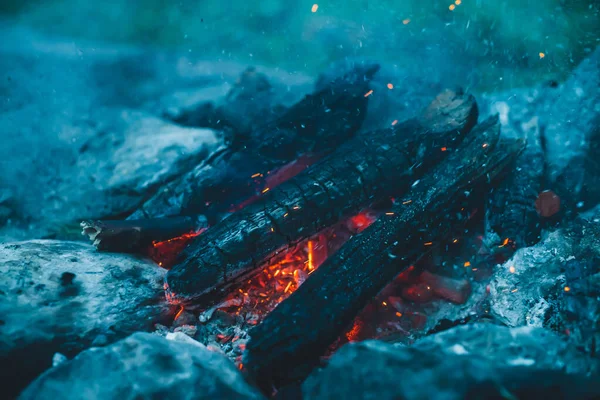 火の近くで焼かれた鮮やかな色付きの薪 キャンプファイアと青煙のオレンジの炎と大気暖かい背景 たき火のフルフレームイメージ 空気中のメンバーや灰の美しい旋風 — ストック写真