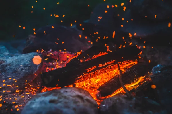 火の密室で焼かれた鮮やかな色付きの薪 キャンプファイアのオレンジ色の炎で大気中の背景 空中で輝くメンバーとたき火の素晴らしいフルフレームイメージ 暖かい丸太 明るい火花Bokeh — ストック写真