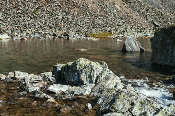 在高山湖水清澈的背景上 长着地衣的大石头 风景秀丽的自然景观 有着巨大的苔藓石和冰湖 漂亮的石头在透明的水中 大气山区风景 — 图库照片