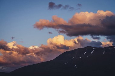 Atmosferik dağ manzarası, şafak vakti leylak rengi gökyüzü. Dağlarda gün batımını aydınlatan manzaralı bir manzara. Dağlarda, pastel tonlarda güzel bir gündoğumu. Şafak vakti bulutlu gökyüzünde aydınlatıcı bir renk.