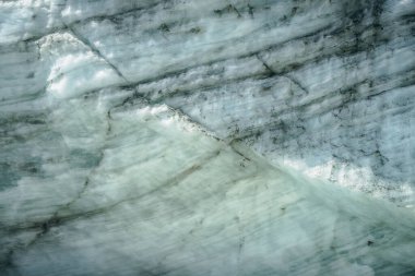 Buzul yüzeyinin minimalist arka planında çatlaklar ve çizikler var. Güneş ışığında buzlu duvarın minimum doğal arkaplanı. Parlak buzul yüzeyi. Buzul duvarının güzel doğa dokusu.