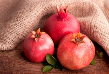 Olgun nar. Koyu arkaplandaki tahtanın üzerinde yapraklar var.