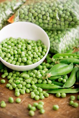 Fotokopi alanı ve doğal ahşap masası olan ahşap zemin üzerinde yeşil bezelye kasesi.