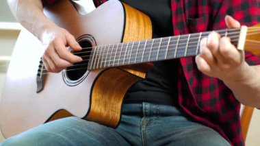 Genç bir adam internet, dizüstü bilgisayar ve online ders kullanarak gitar çalmayı öğreniyor. Hobi ve eğlence konsepti