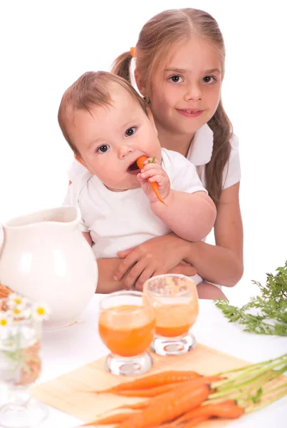 Dívka a malý chlapec, bratr a sestra a mrkvová šťáva izolované na bílém pozadí — Stock fotografie