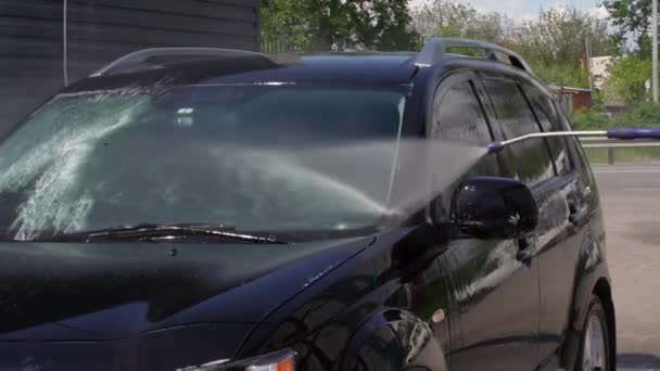 屋外の高圧水の下で車を洗う男のショット. — ストック動画