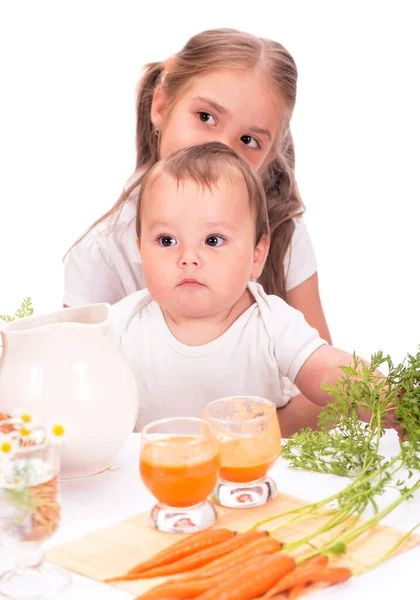 Mädchen und kleiner Junge, Bruder und Schwester und Karottensaft isoliert auf weißem Hintergrund — Stockfoto