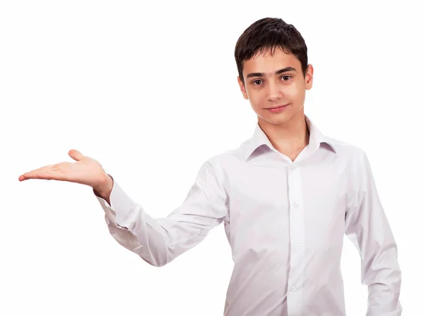 Smiling guy in white clothes on a white background looks at the camera and shows an empty palm. Cheerful young man in white shirt shows on blank space — Stock Photo, Image