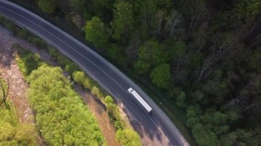 Yazın günbatımında güzel yeşil ormandaki hava manzaralı yol. Yolları, çam ağaçları, bulanık arabaları ve Carpatian dağlarındaki nehri olan renkli bir manzara. Otobanın üst manzarası. Ukrayna 'da Seyahat
