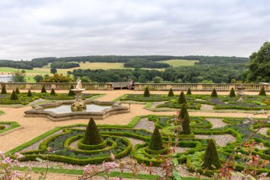 Parterre gardens with triton fountain and topiary shrubs.  Rural scene view beyond the gardens at the Harewood House estate. clipart