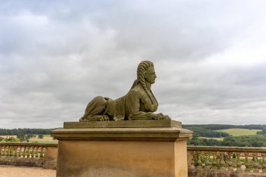 Batı Yorkshire, İngiltere - 26 Ağustos 2021: Antik taş oyulmuş bir sfenks heykeli, ünlü bir anıt, Leeds yakınlarındaki Harewood House bahçelerinde insan başlı bir aslan tasvir ediyor.