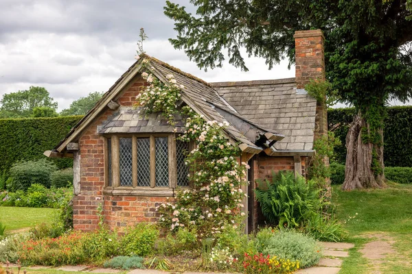 非常古老的红砖小花园房子 有石板屋顶 复盖的窗户和粉色的攀爬 — 图库照片