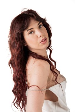 Kızıl saçlı, uzun dalgalı saçlı, beyaz bluzlu bir kadın. Beyaz arka planda kameraya bakıyor.