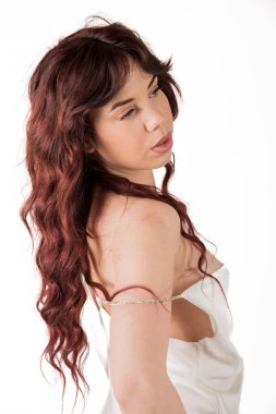 Kızıl saçlı, uzun dalgalı saçlı ve bilezik takmış bir kadın stüdyo resminde omzunun üzerinden geriye bakıyor.