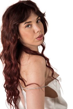 Kızıl dalgalı saçlı bir kadın portre için poz veriyor, beyaz arka planda omzunun üstünden bakıyor. Güzellik ve zarafet konsepti