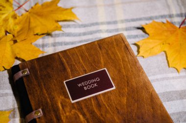 Deri kaplı, çikolata renkli etiketli ahşap kapaklı bir düğün kitabı. Kitap kapağının etiket ve ahşap dokusuna yakın plan